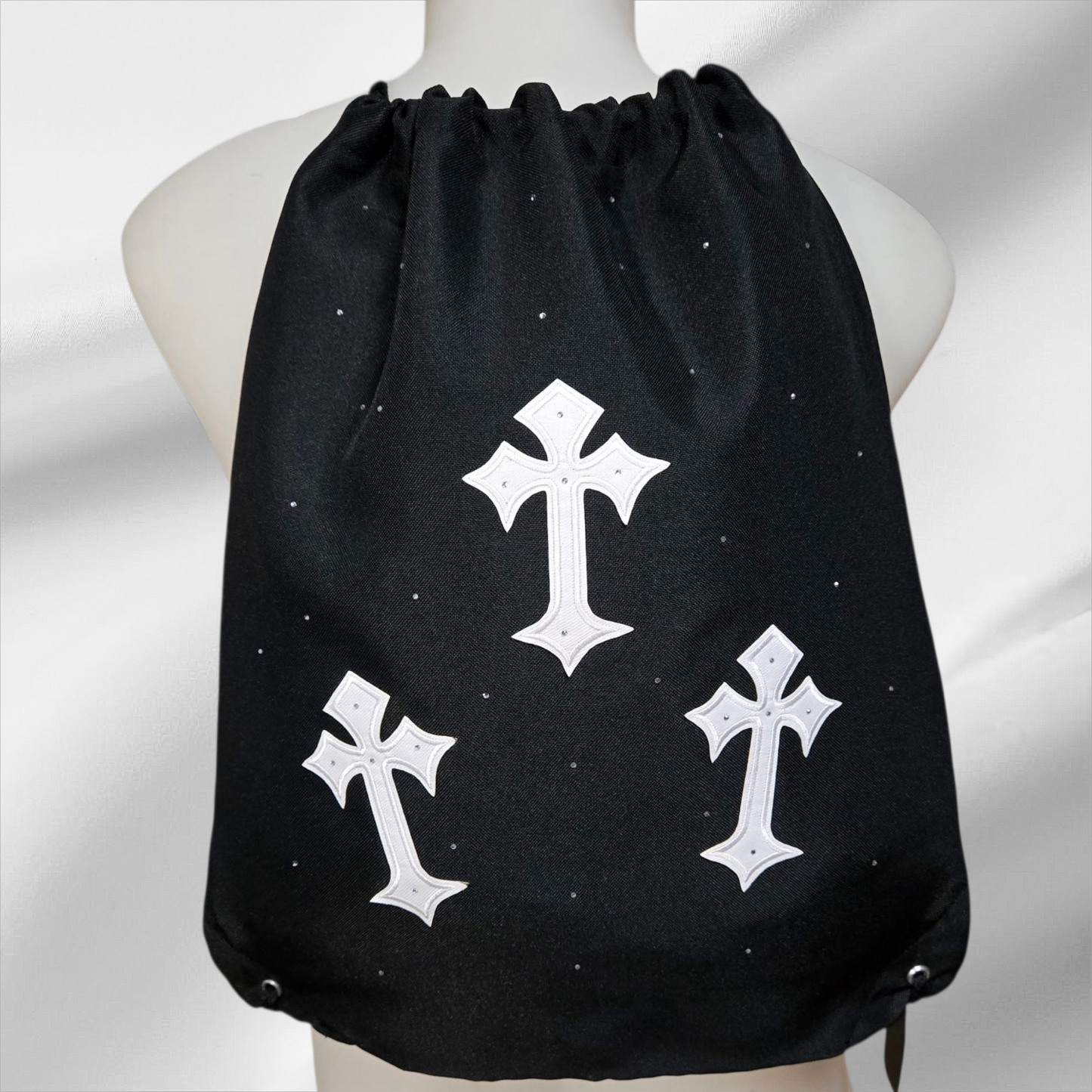 Black drawstring bag with white cross patterns embellished in rhinestones